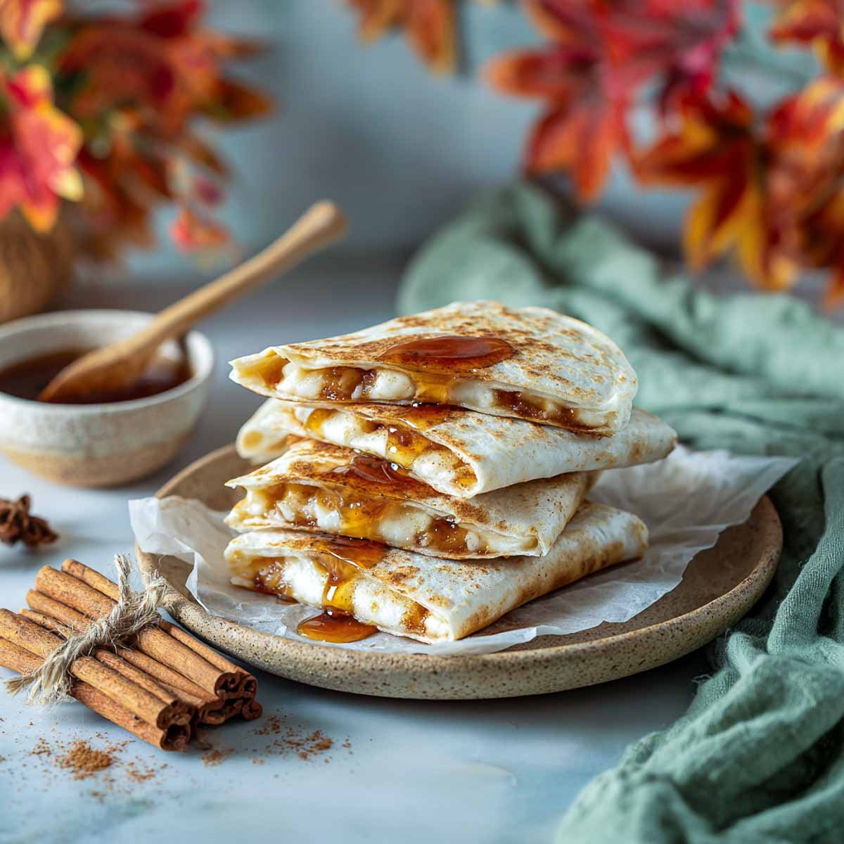 Stacked maple cinnamon quesadillas drizzled with syrup on stoneware plate.