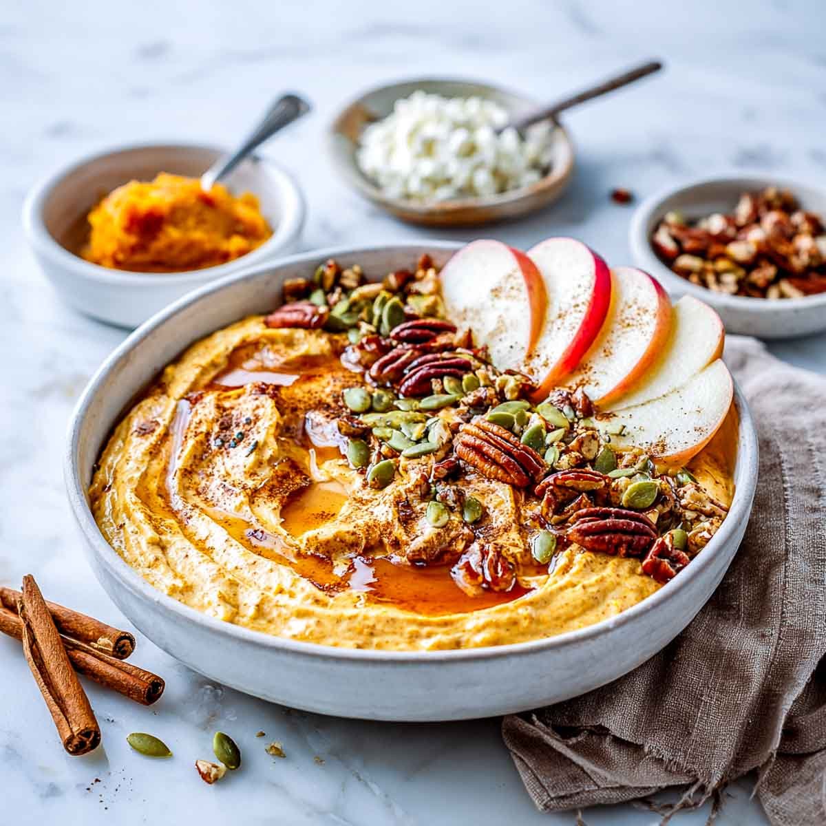 Pumpkin cottage cheese bowl topped with pecans, apples, and maple drizzle.