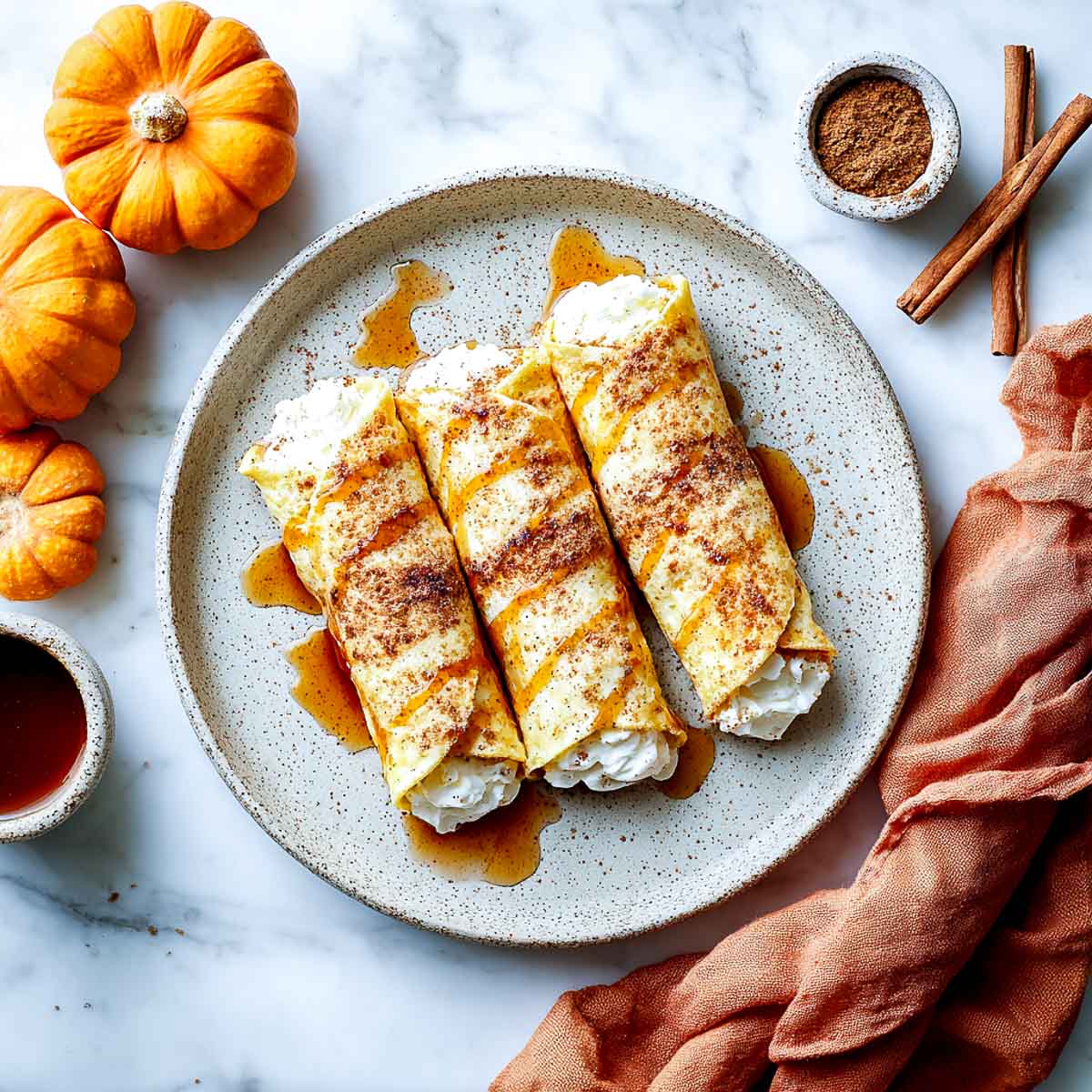 Three pumpkin roll ups filled with whipped cottage cheese and maple drizzle.