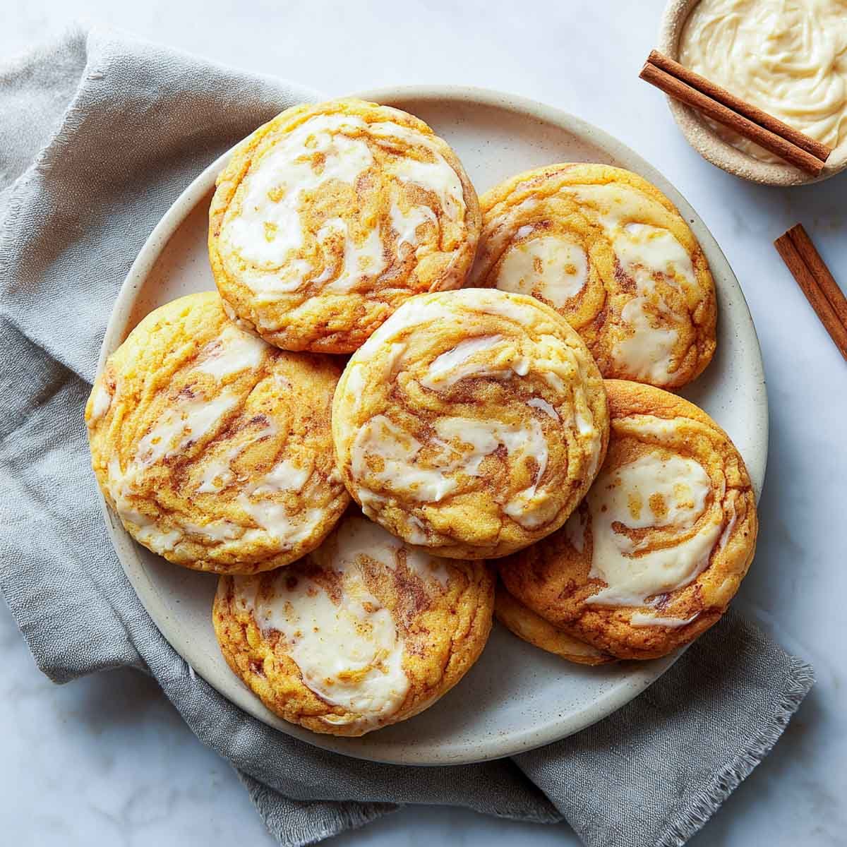 Pumpkin cookies with baked-in cream cheese swirls and golden edges.