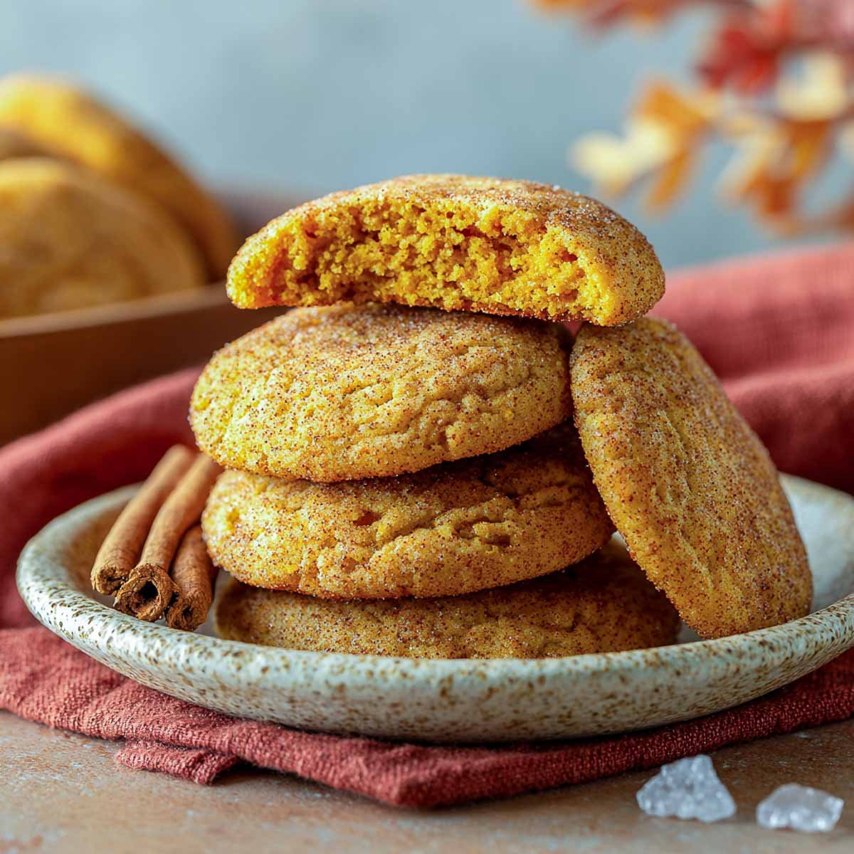 Pumpkin snickerdoodle cookies coated in cinnamon sugar with cracked tops.