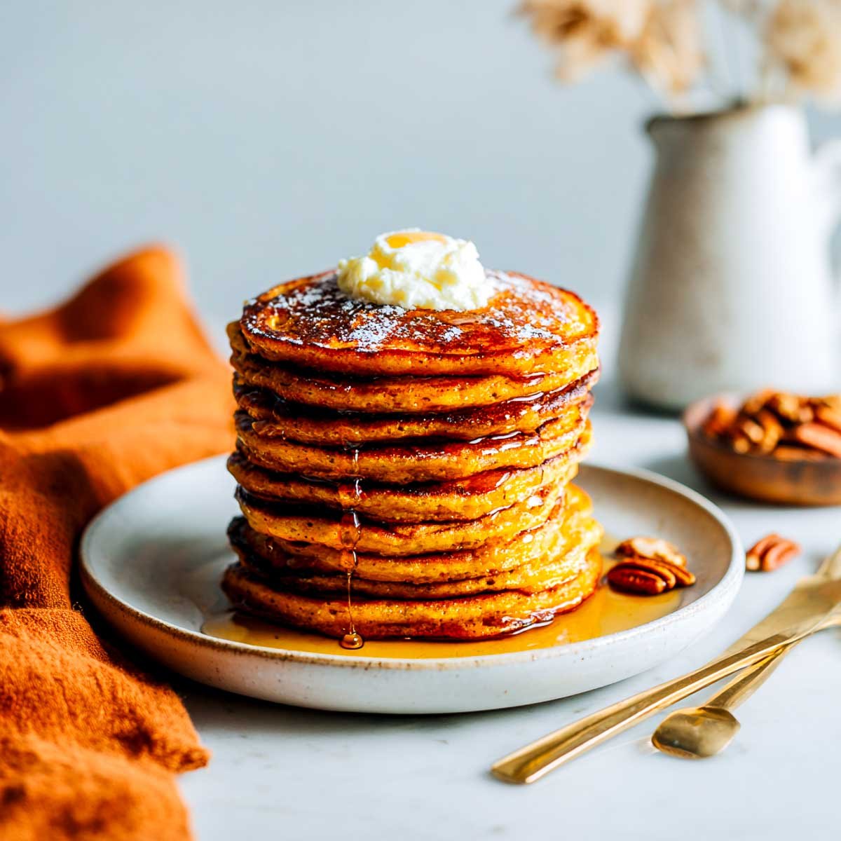 Stack of pumpkin spice cottage cheese pancakes with syrup and butter.