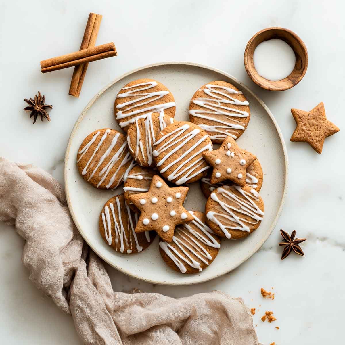 Top-down view of vegan gingerbread cookies with white icing and star anise.