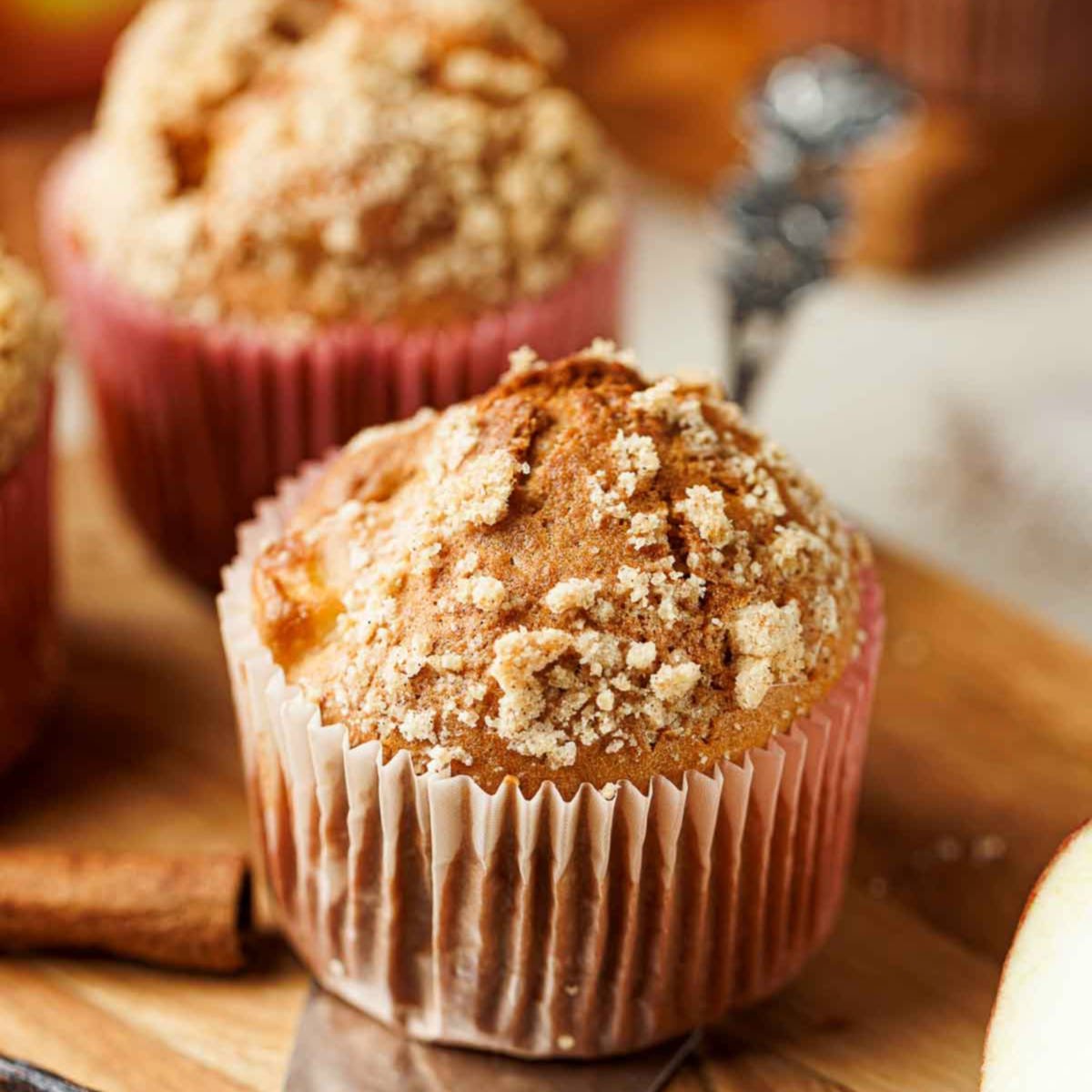 Apple cinnamon muffin topped with buttery crumb topping in a pink liner.
