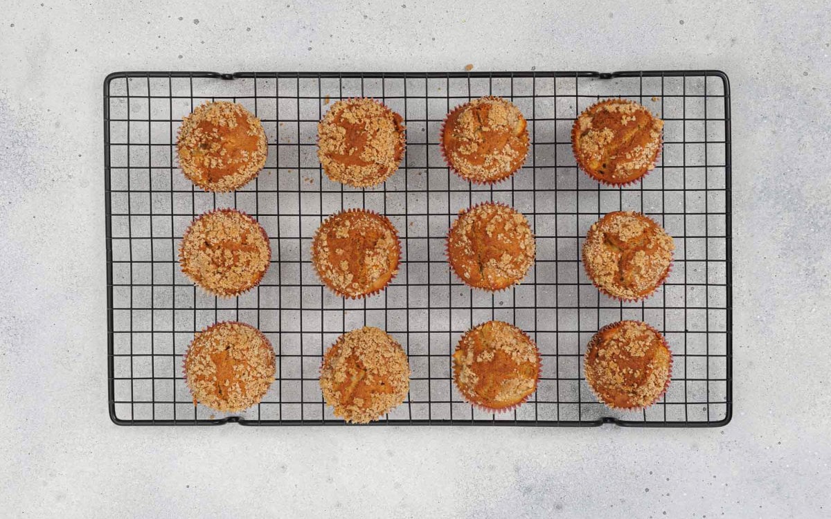 Freshly baked apple cinnamon crumb muffins cooling on a wire rack.