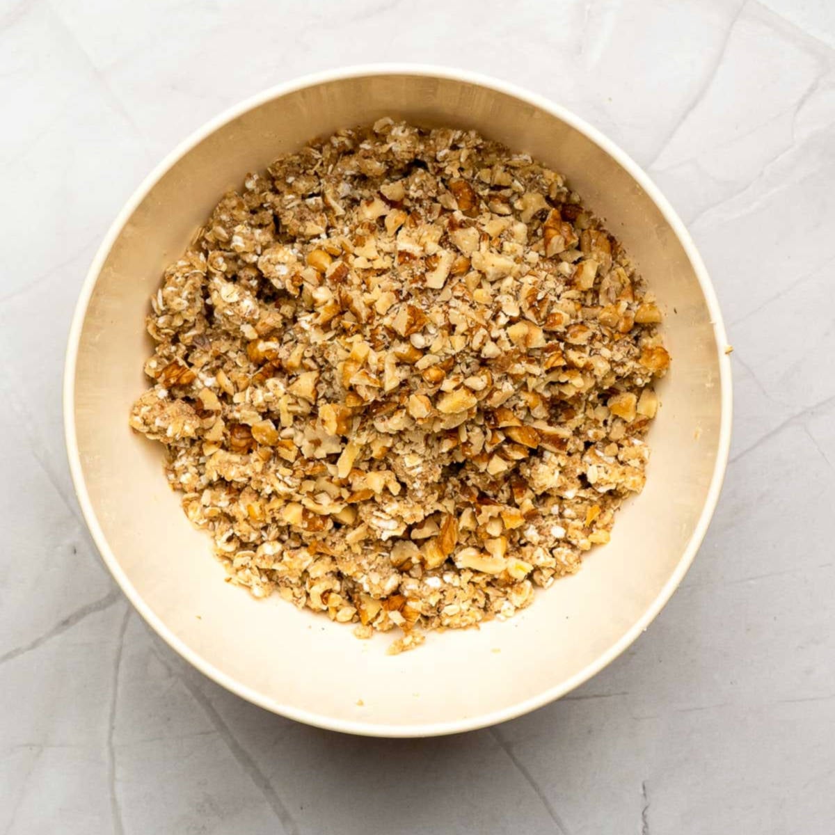 Oat, flour, sugar, and nut mixture for apple crisp topping in a mixing bowl.