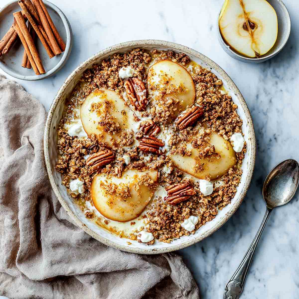 Baked pear crumble with dairy-free cottage cheese and pecans in a ceramic dish.