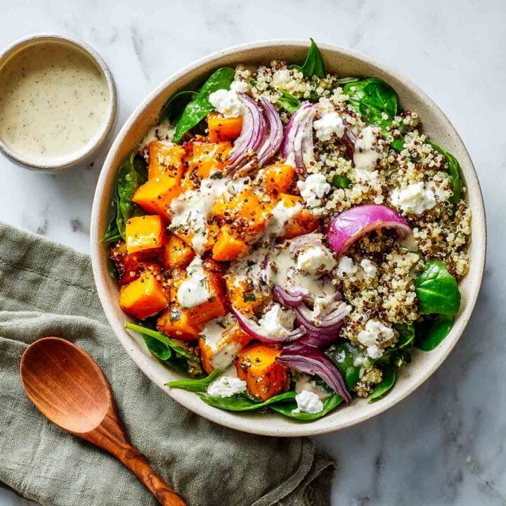 Power bowl with quinoa, spinach, squash, vegan cottage cheese, and dressing.
