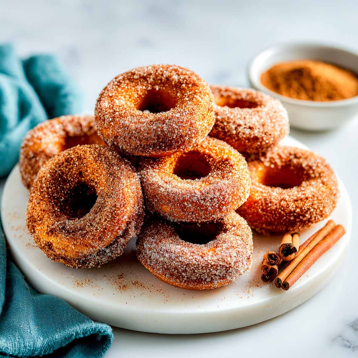 Baked vegan sweet potato donuts coated in cinnamon sugar on a serving tray.