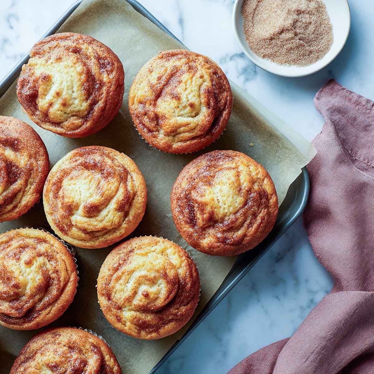 Cinnamon swirl muffins with dairy-free cottage cheese on a parchment-lined tray.