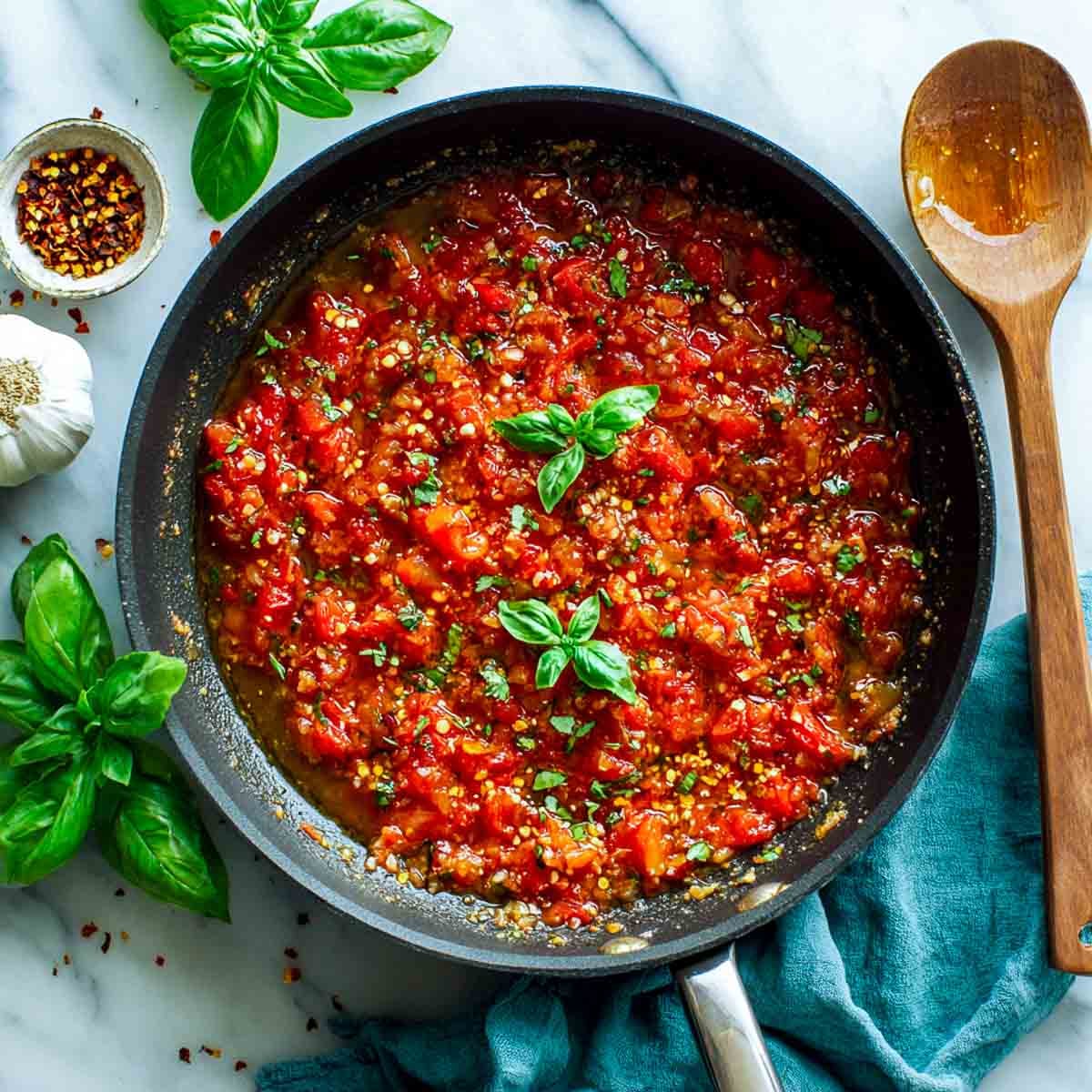 Tomato sauce simmering in a skillet with garlic and red pepper flakes.