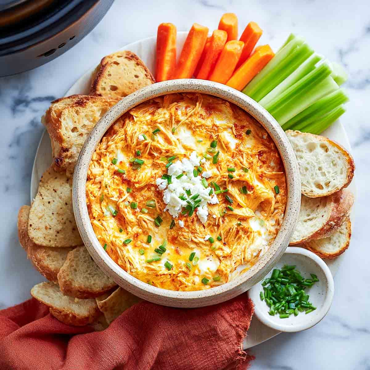 Buffalo chicken dip with cottage cheese, carrots, celery, and crusty bread slices.