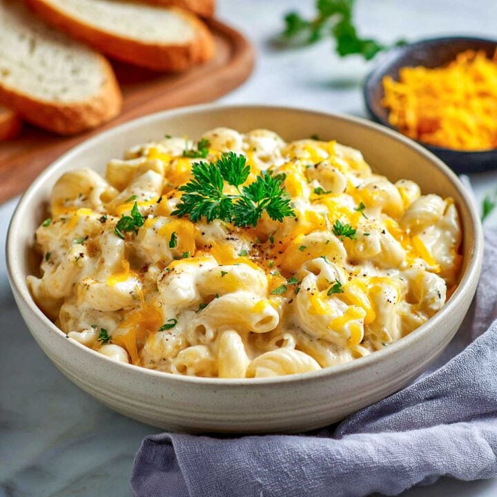 Serving bowl of crockpot cottage cheese mac and cheese with parsley garnish.