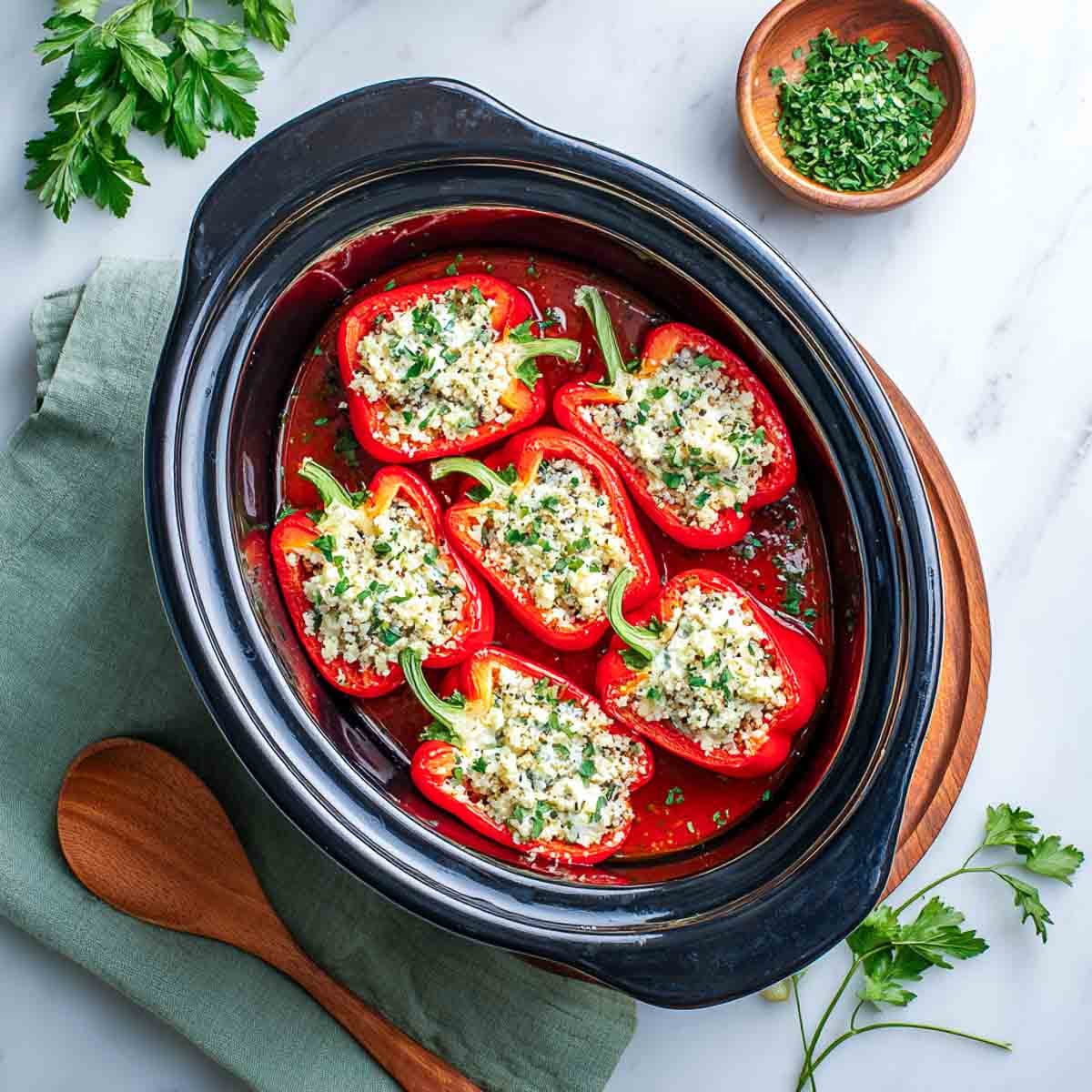 Red bell peppers stuffed with cottage cheese filling in crockpot.