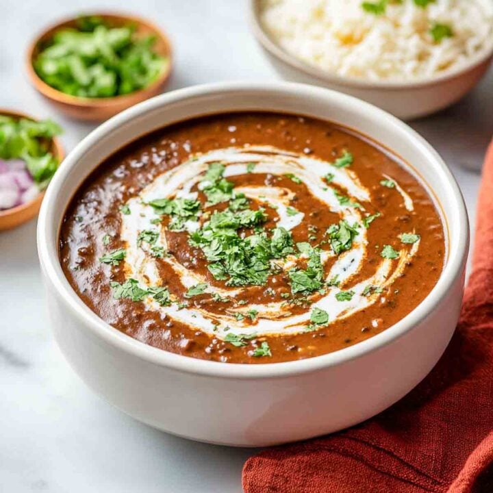Dal makhani served in a white bowl with rice in the background.