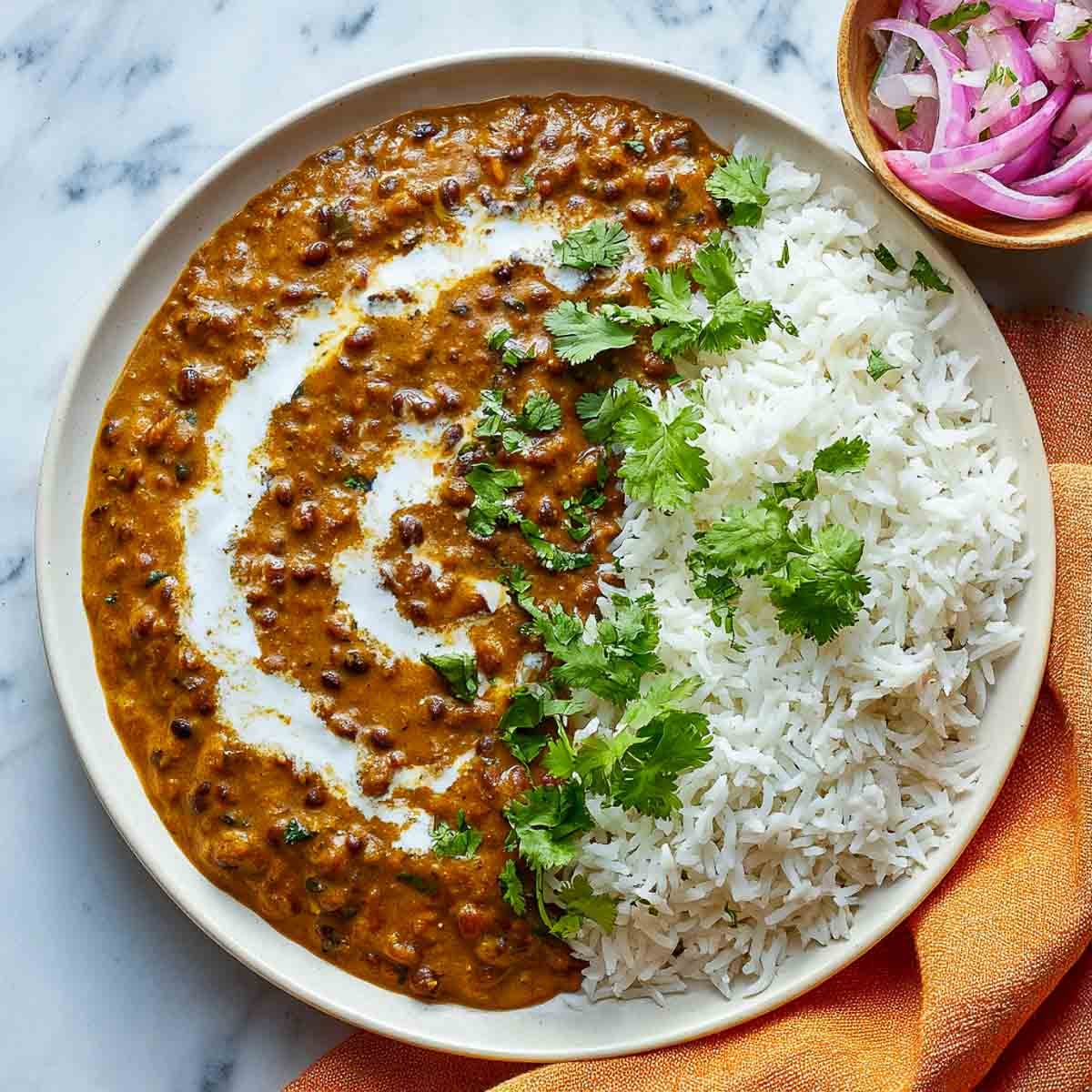 Dal makhani served on a white plate along with rice.
