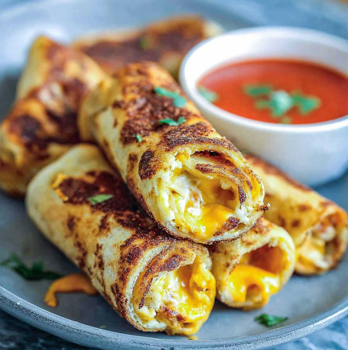 Grilled cheese roll-ups with melted centers and tomato soup for dipping.