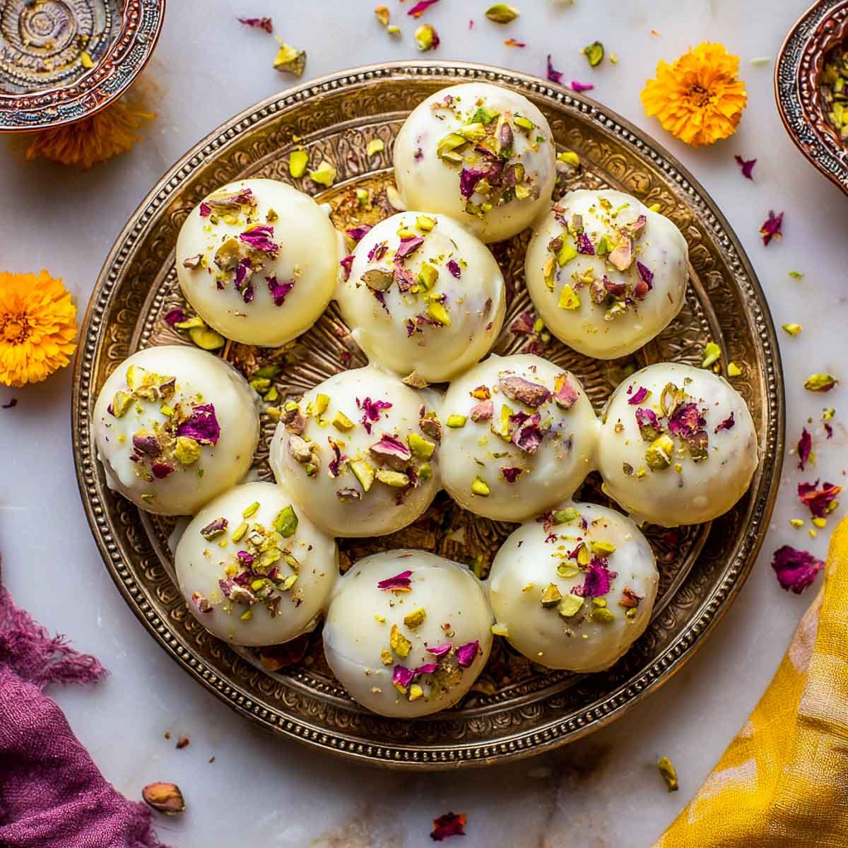 Overhead of gulab jamun truffles with pistachios and rose petal garnish.