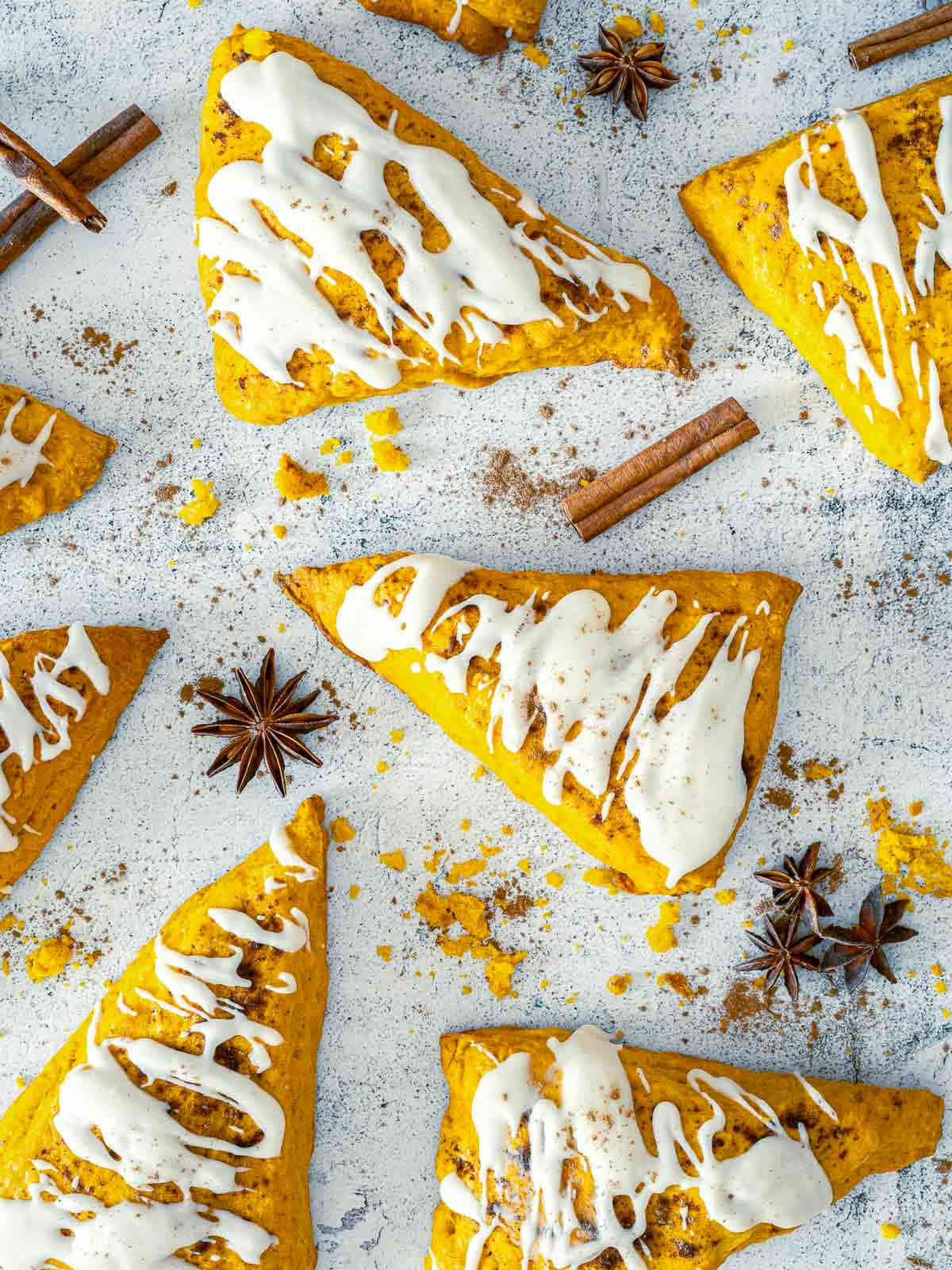Pumpkin spice scones with vanilla glaze surrounded by cinnamon sticks and star anise.