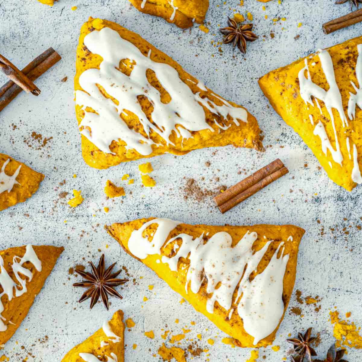 Pumpkin spice scones with vanilla glaze and scattered fall spices overhead.