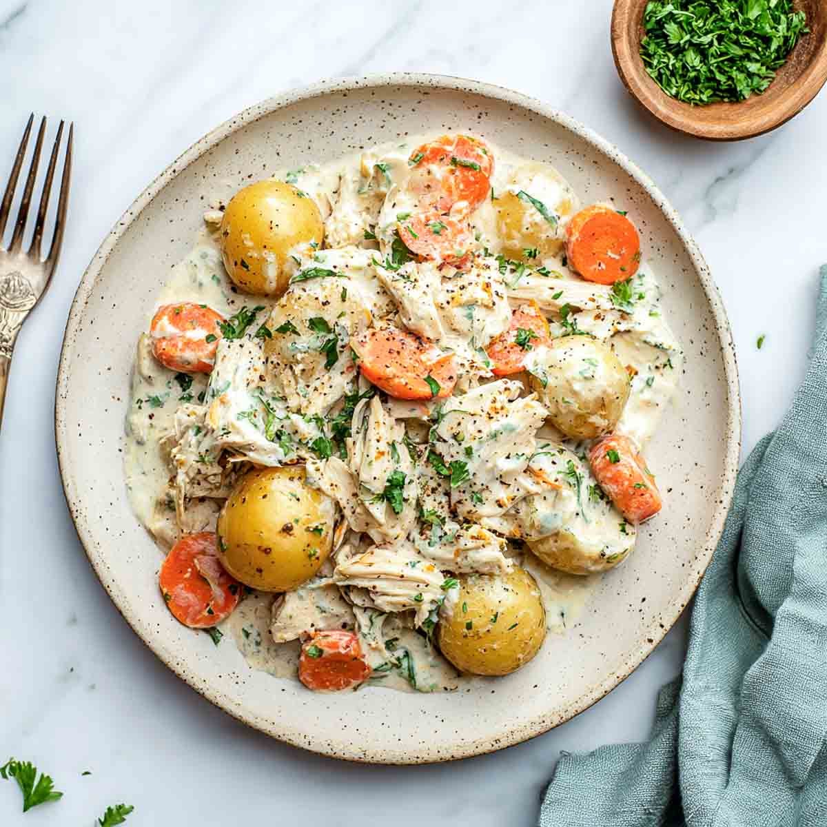 Top-down view of creamy ranch chicken with carrots and baby potatoes.