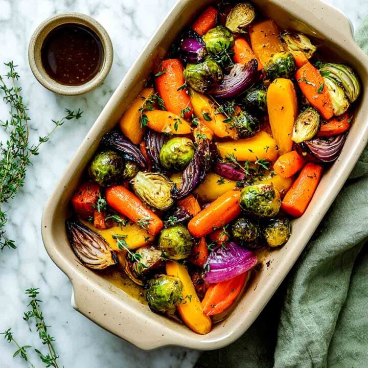 Roasted autumn vegetables with maple balsamic glaze in baking dish.