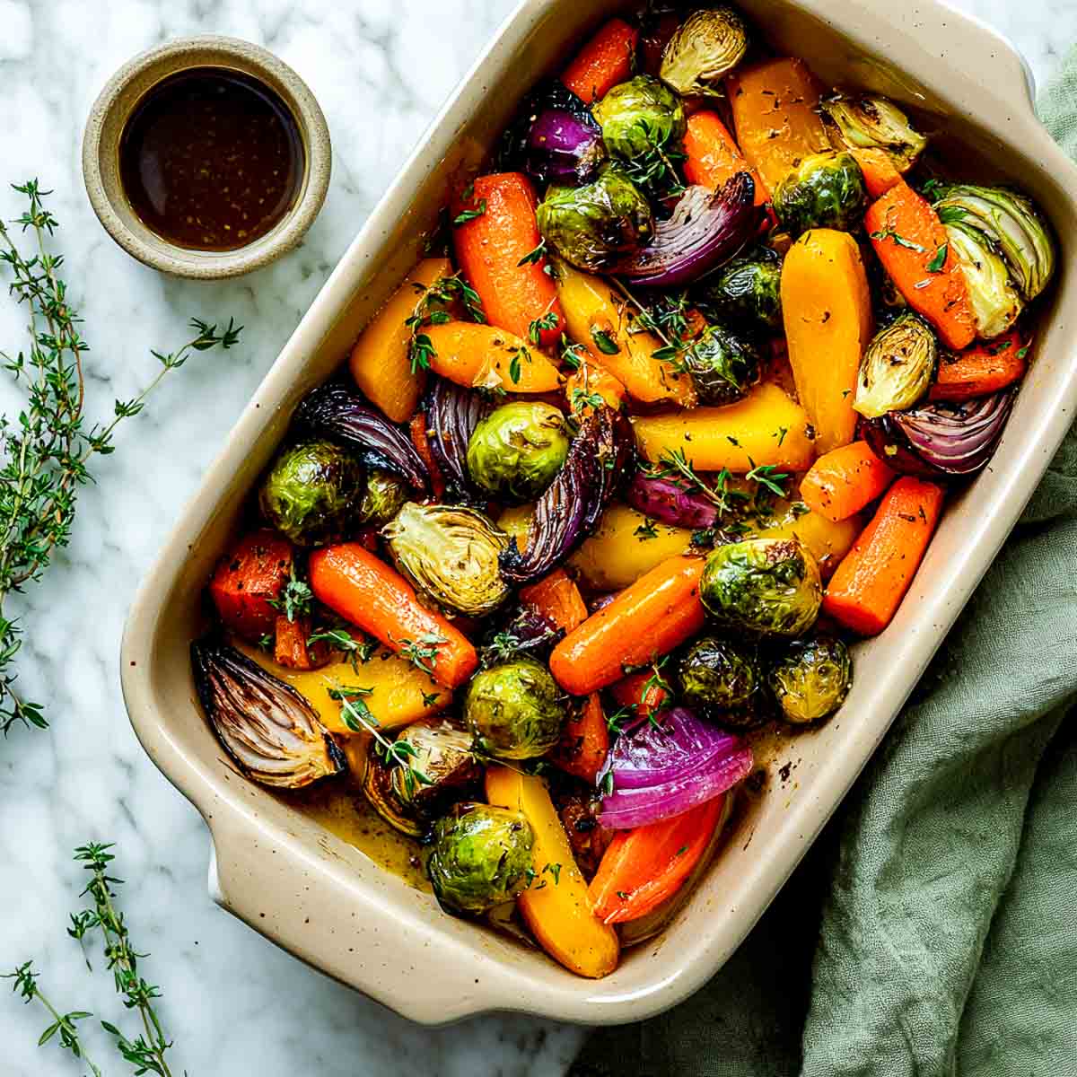 Roasted autumn vegetables with maple balsamic glaze in baking dish.