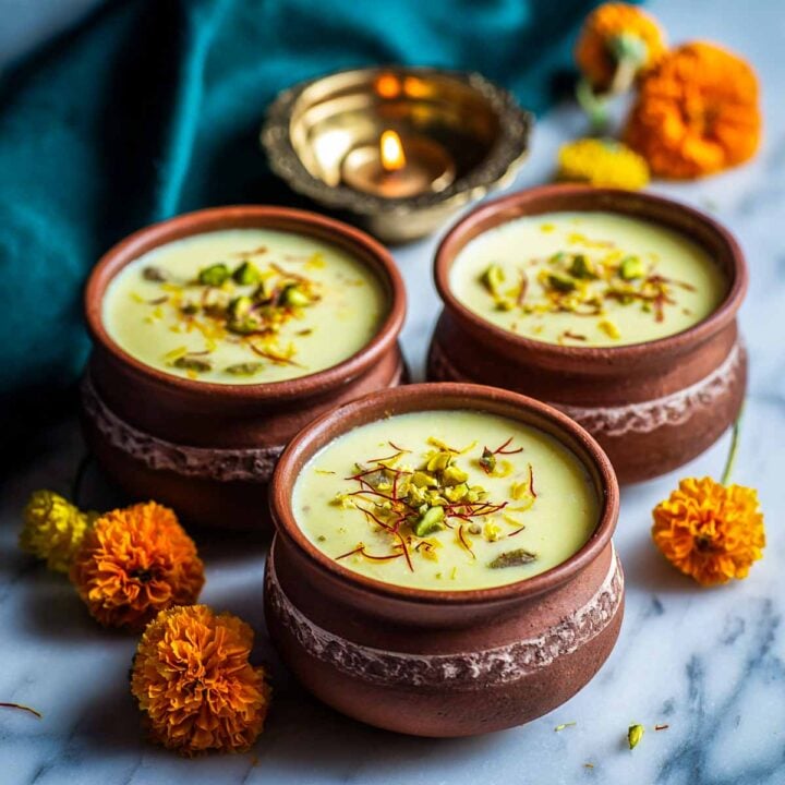 Mini clay pots filled with saffron pistachio phirni, garnished with nuts.