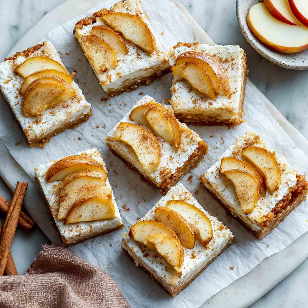 Apple pie bars with cottage cheese and sliced apples on parchment paper.