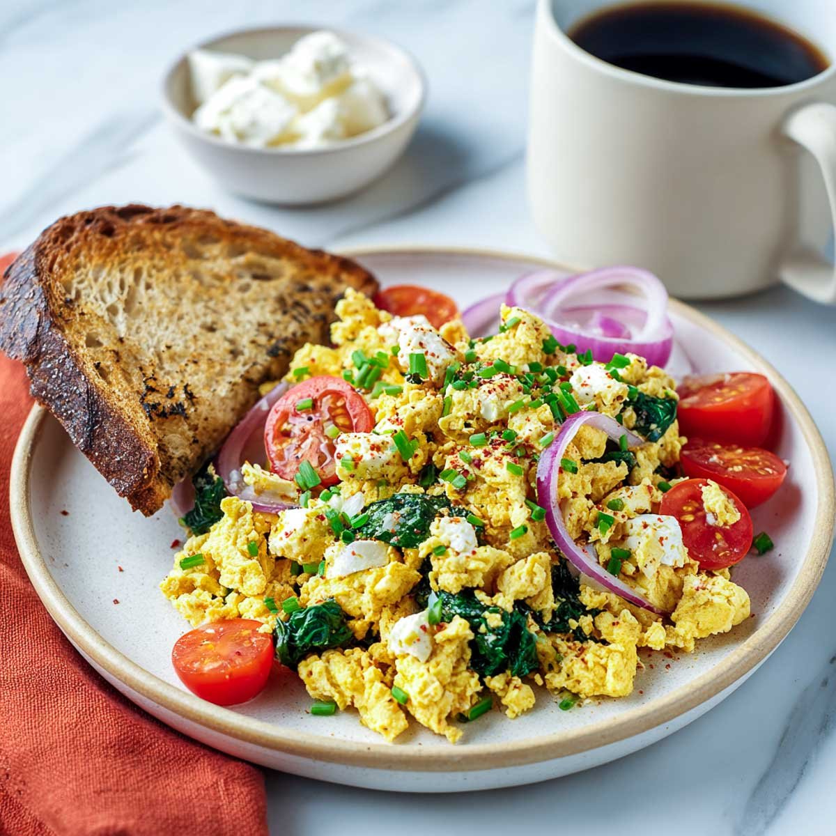 Savory tofu scramble with vegan cottage cheese, spinach, and cherry tomatoes.