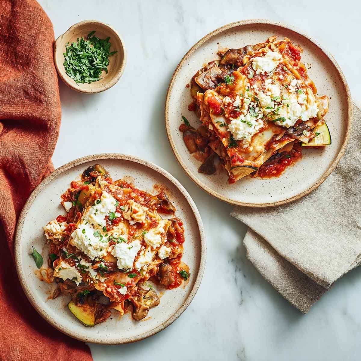 Two rustic servings of vegan crockpot lasagna topped with cottage cheese.
