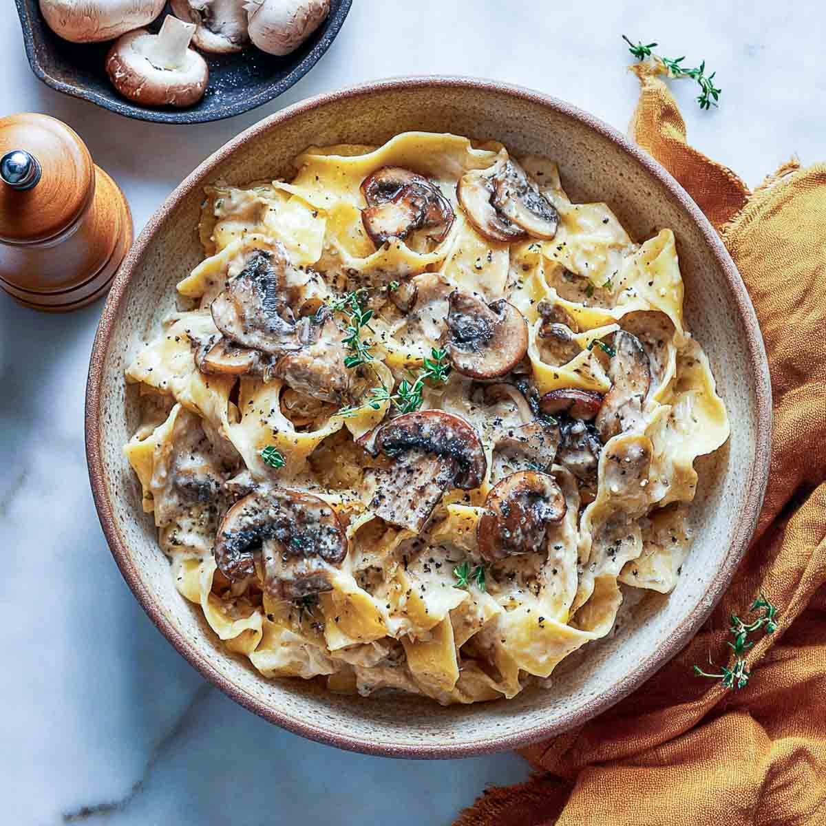 Creamy mushroom stroganoff with pappardelle and dairy-free cottage cheese in a bowl.