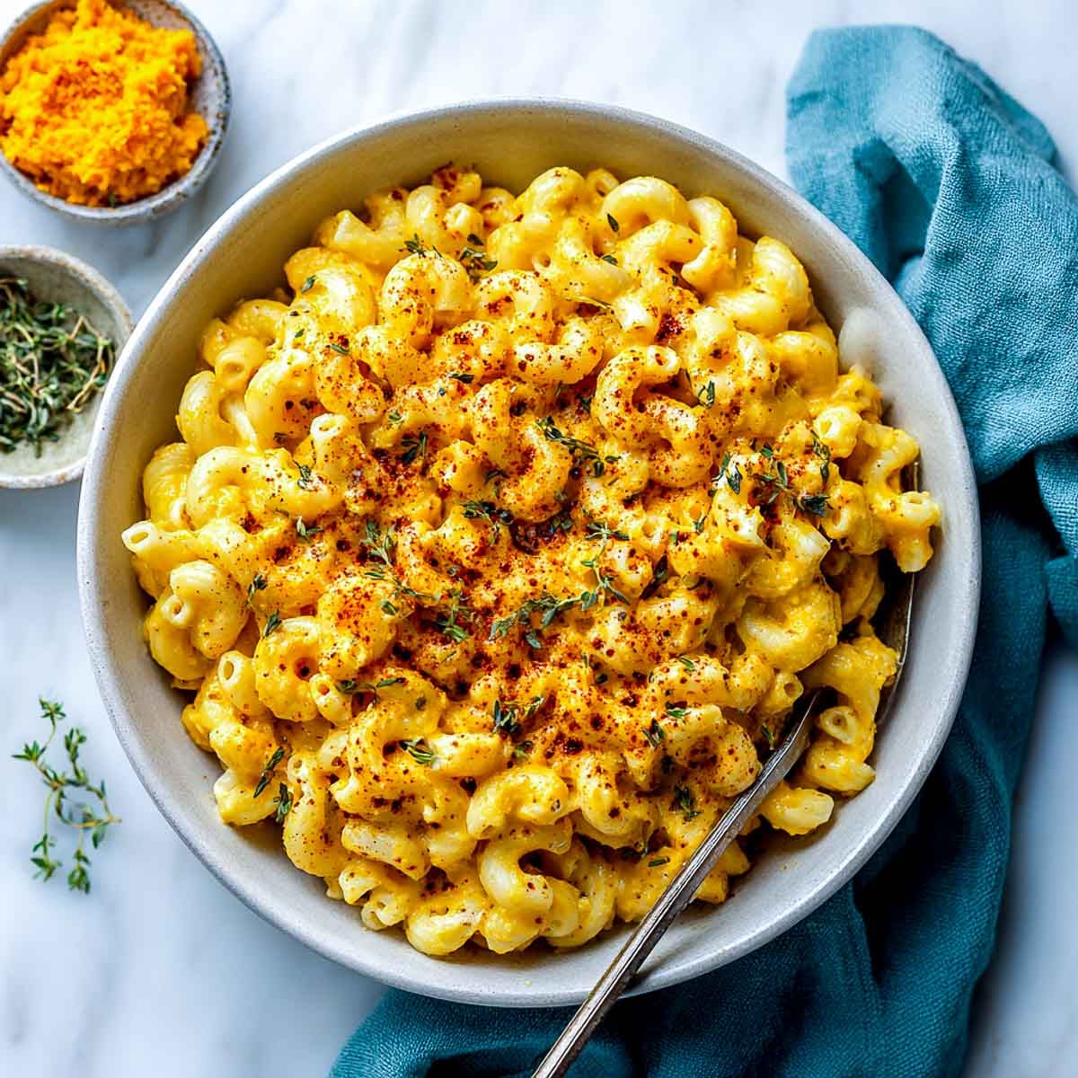Bowl of vegan pumpkin mac and cheese with paprika and thyme garnish.