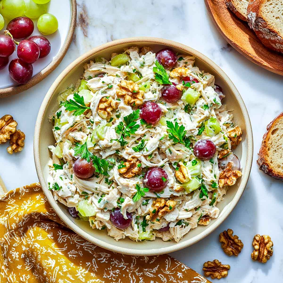 Creamy chicken salad with grapes, walnuts, and parsley in a bowl.