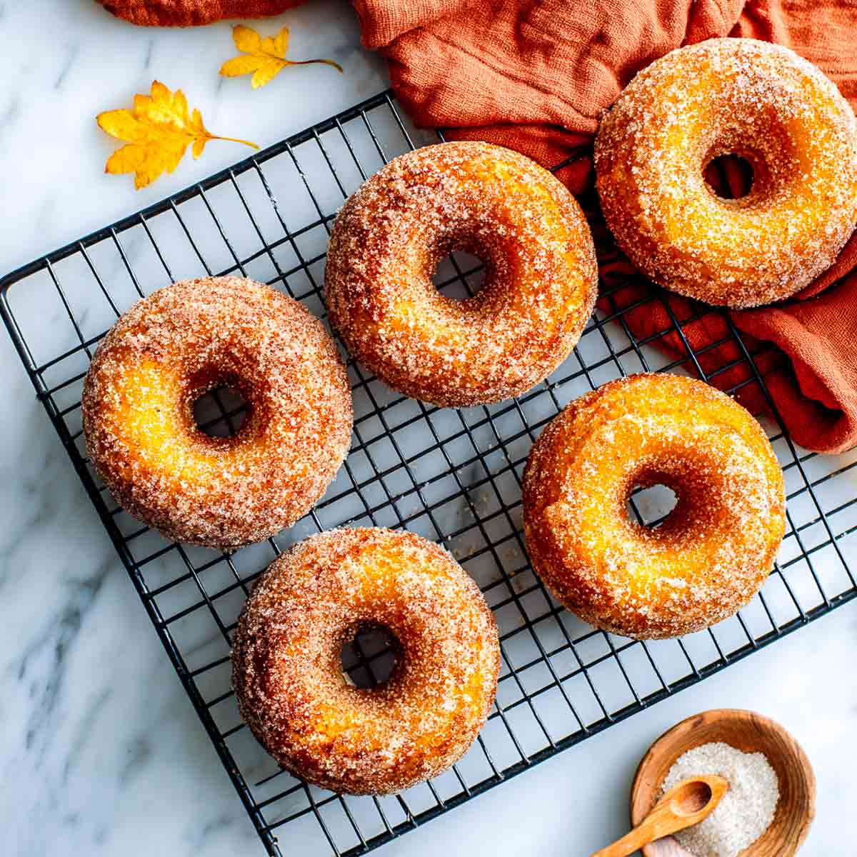 Pumpkin cottage cheese donuts cooling on a rack with sugar topping.