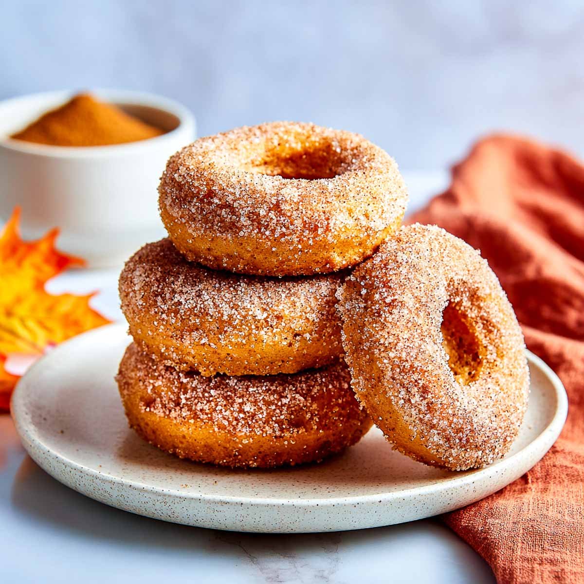 Stack of baked pumpkin cottage cheese donuts coated in cinnamon sugar.