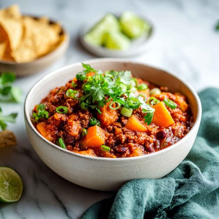 Hearty turkey chili with butternut squash, beans, and fresh herbs in a cream bowl.