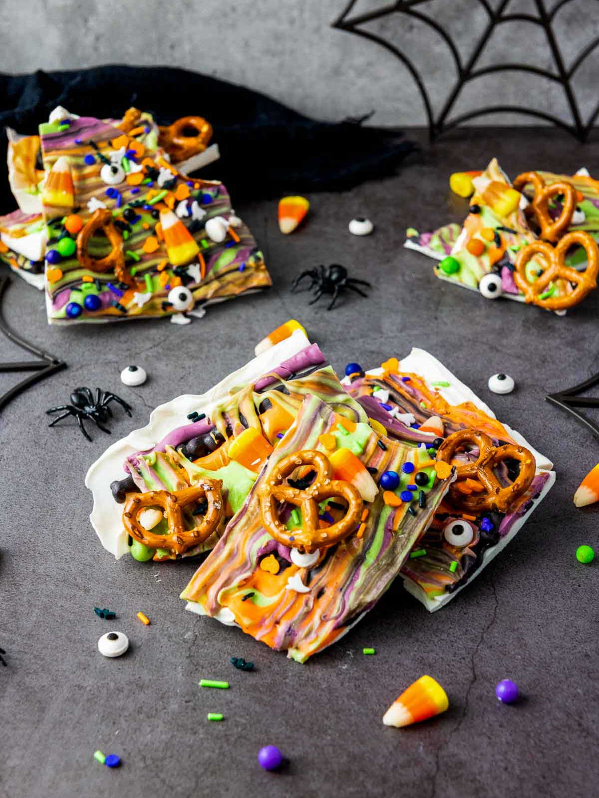 Festive Halloween bark pieces decorated with candy eyes, pretzels, and sprinkles.