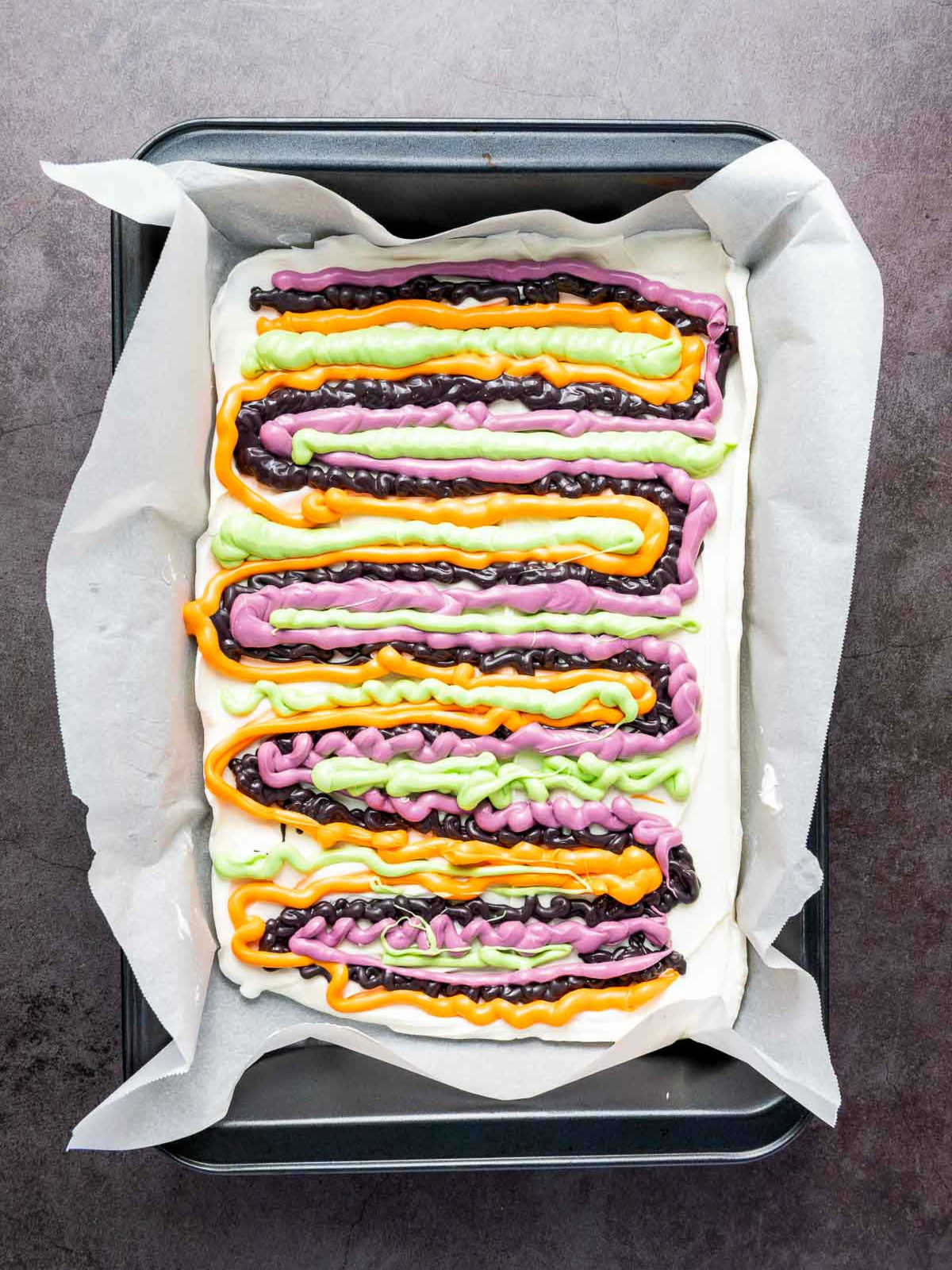 Stripes of colorful candy melts piped over white chocolate base.