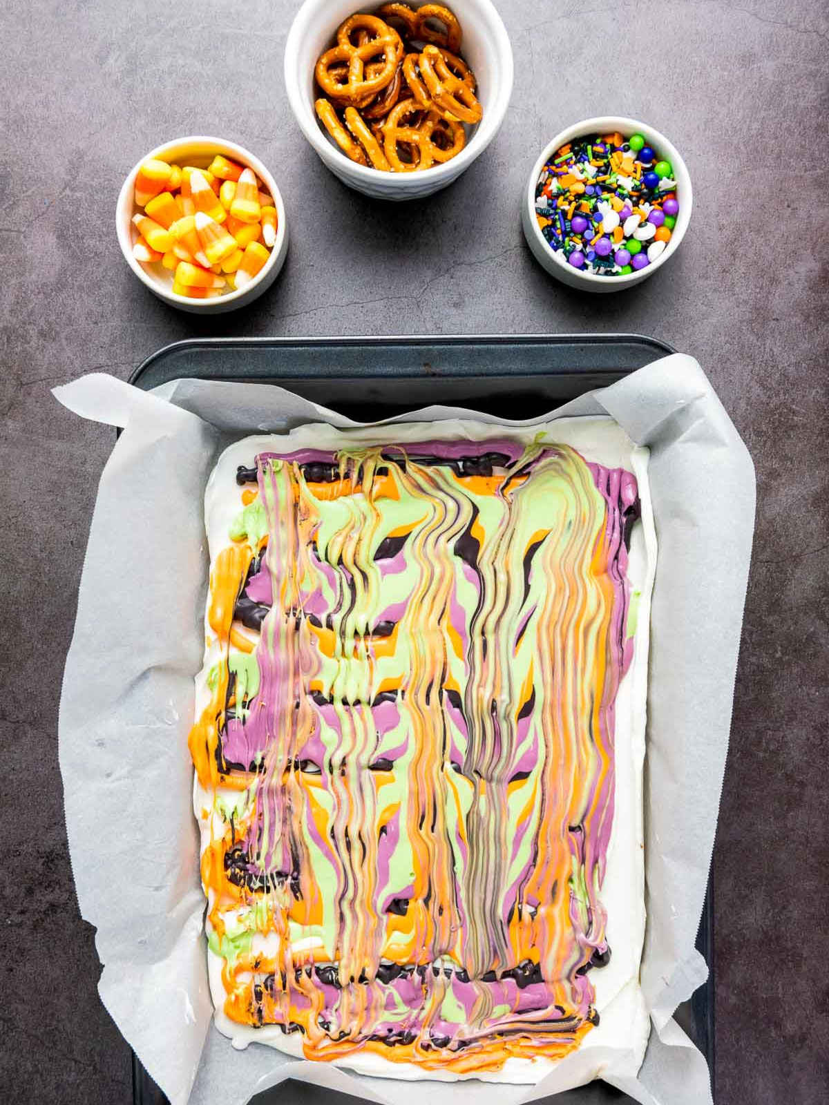 Swirled colorful bark base with bowls of toppings ready nearby.