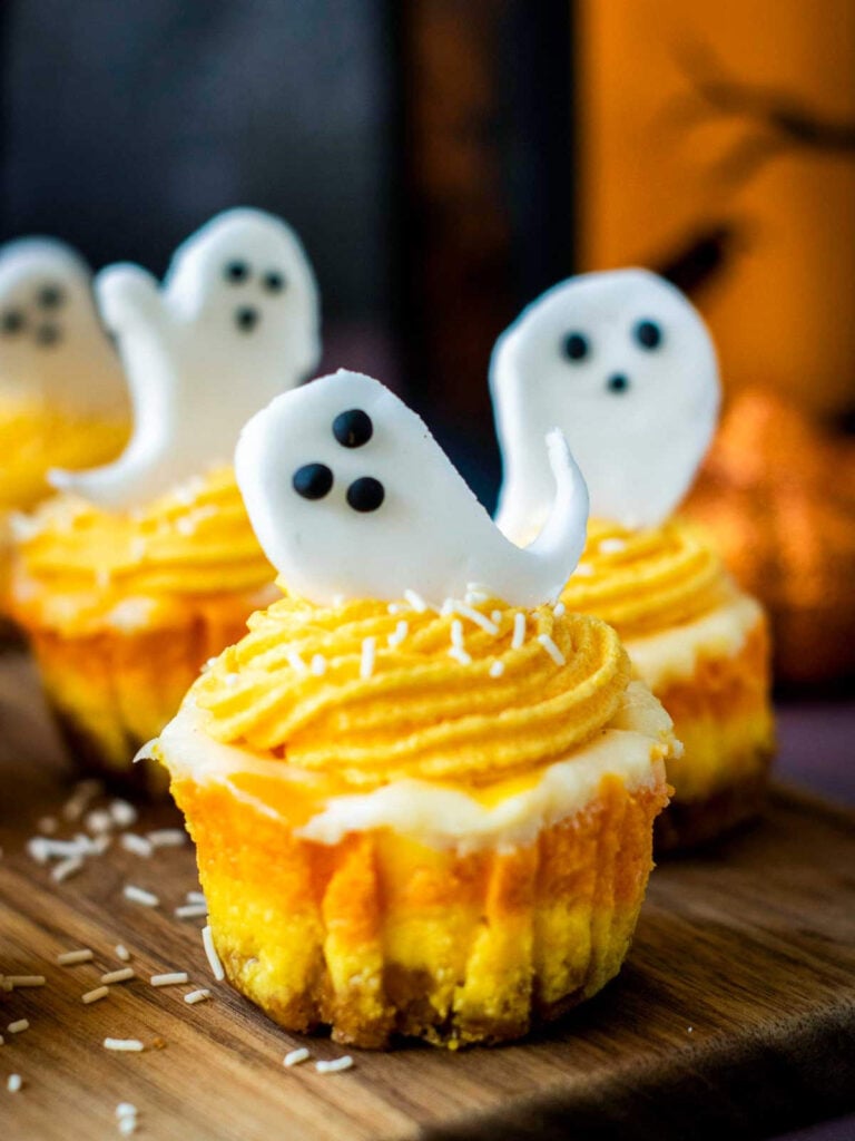 Side view of ghost-topped candy corn cheesecake with layered colors visible.