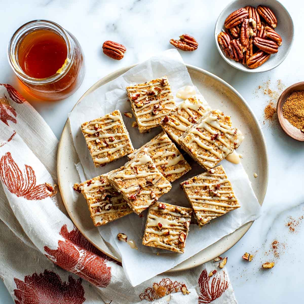 Maple pecan protein bars drizzled with glaze and sprinkled with pecans.