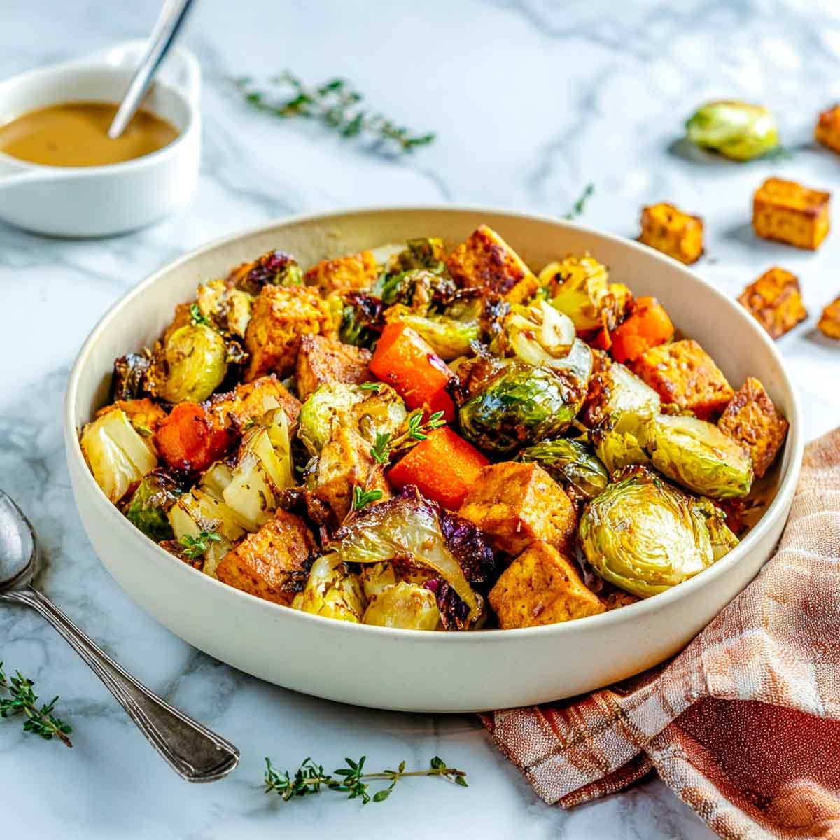 Bowl of maple roasted tempeh with Brussels sprouts, carrots, and sweet potatoes.