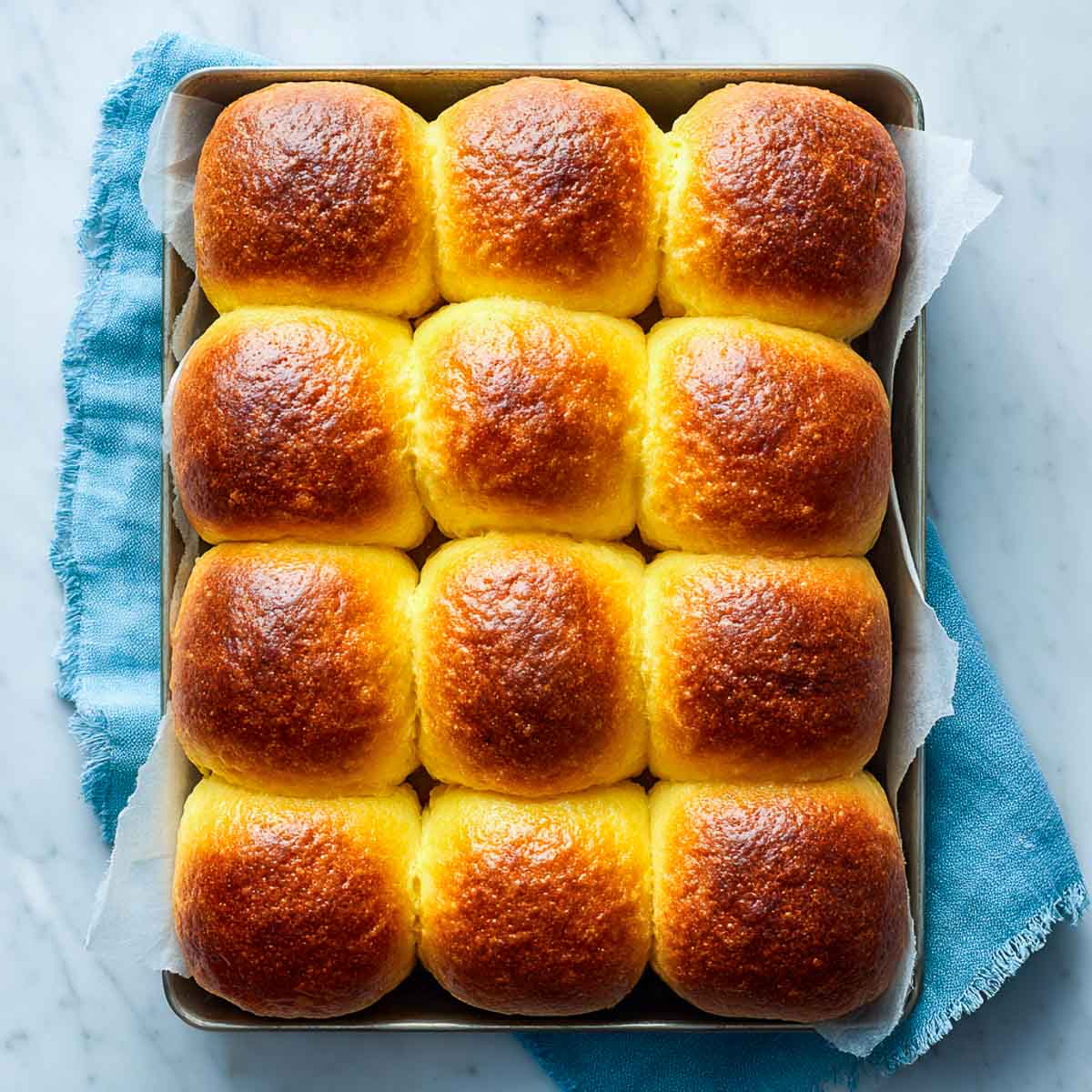 Top view of stuffed bread rolls arranged neatly in a baking tray.