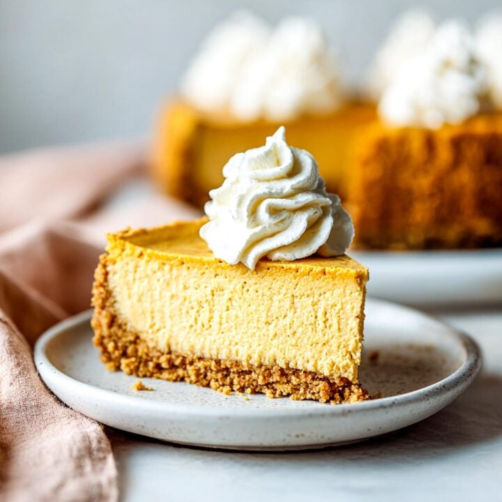 Slice of creamy air fryer pumpkin cheesecake topped with whipped cream.