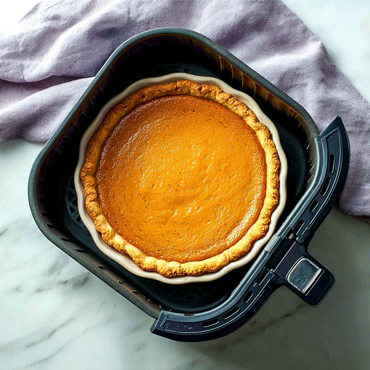 Pumpkin pie baked in air fryer basket with golden flaky crust.