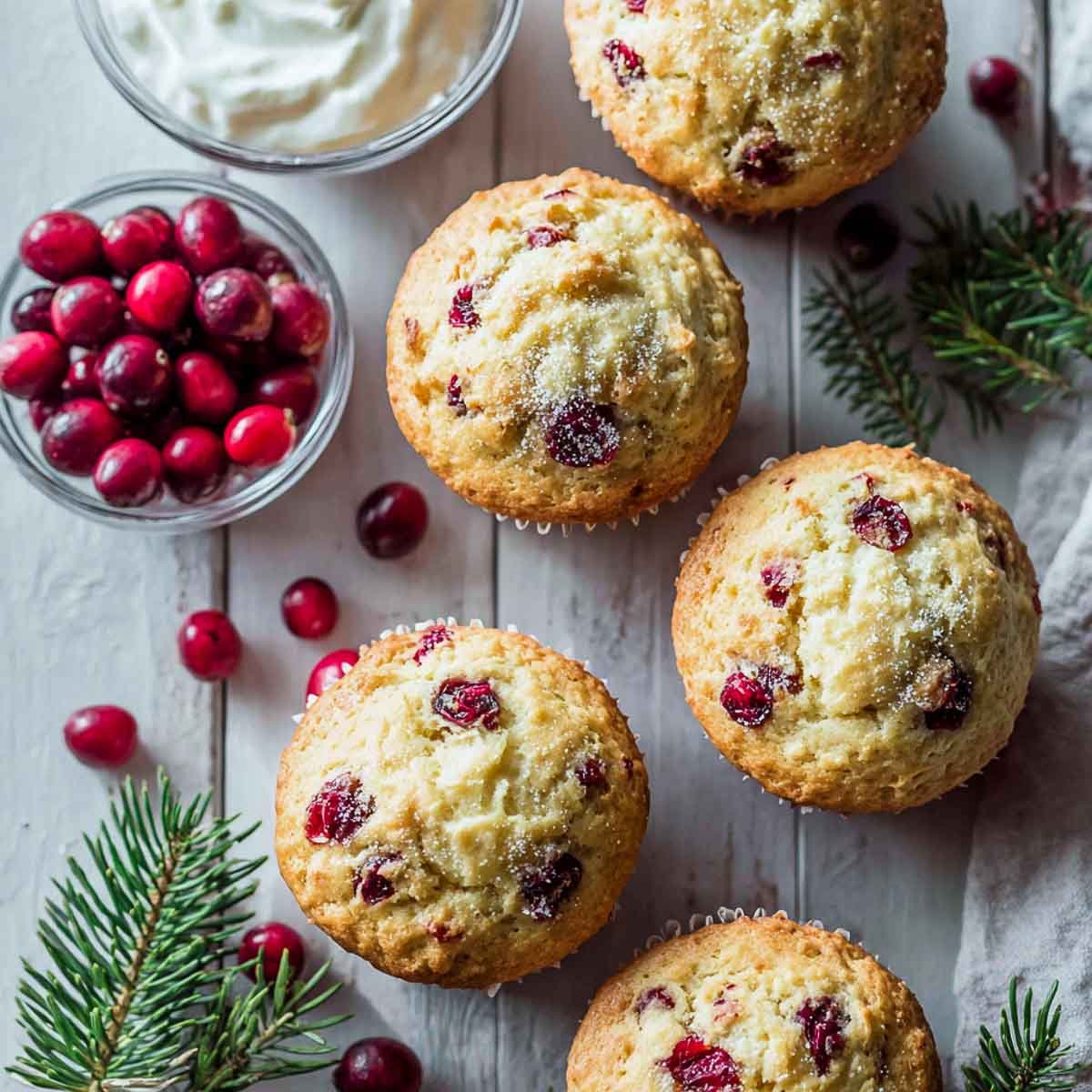 cranberry orange muffins with Greek yogurt on light wood surface.
