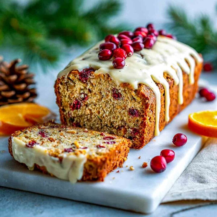 Angled view of cranberry orange oatmeal breakfast loaf topped with glaze and cranberries.