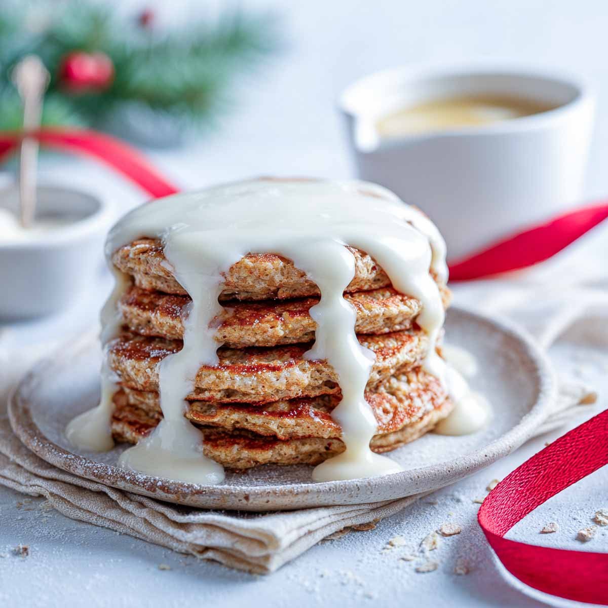 Stack of oatmeal ginger pancakes with Greek yogurt drizzle and lemon zest on a Christmas breakfast table.