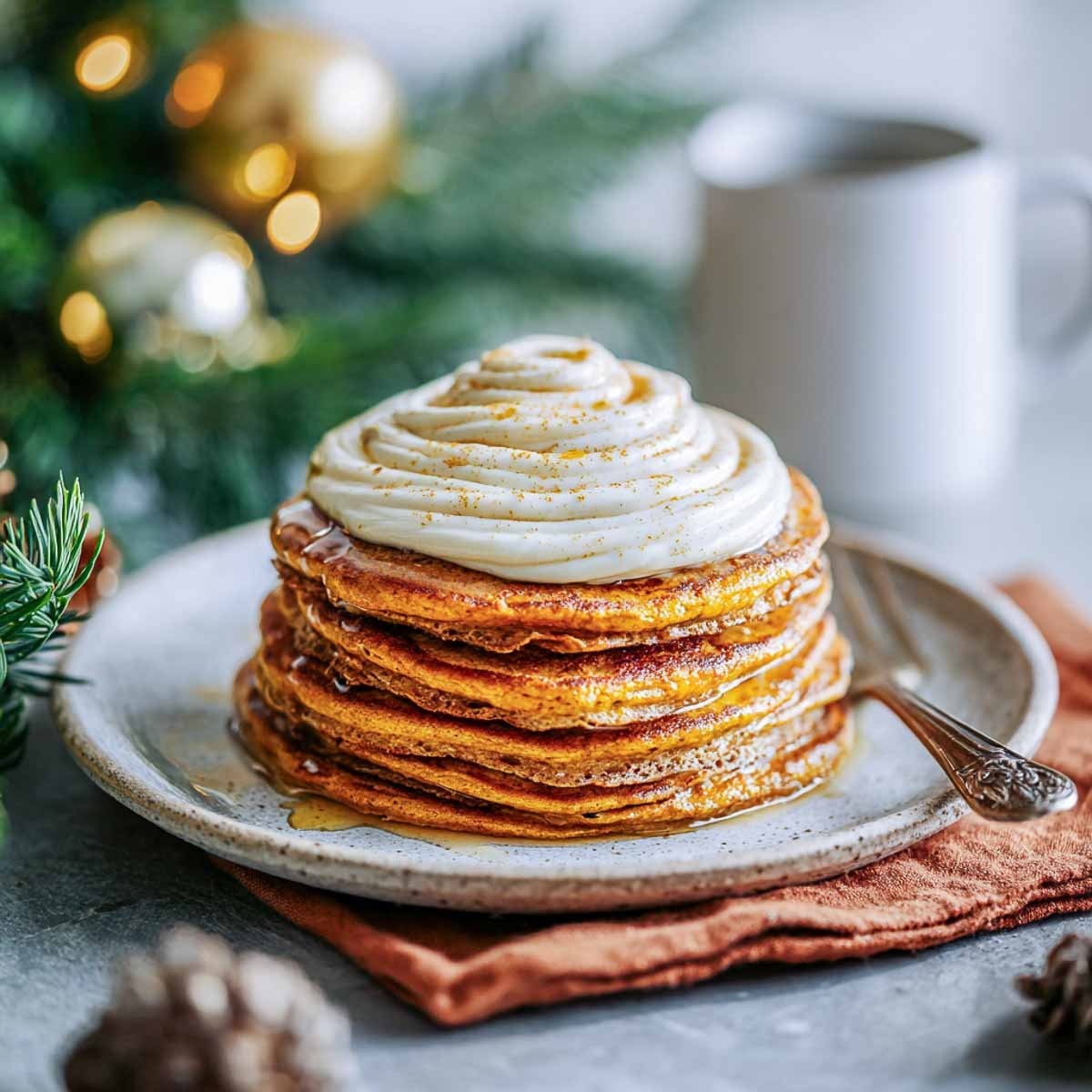 Cozy pumpkin spice breakfast pancakes topped with almond butter frosting and syrup.